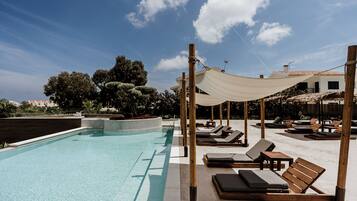 Un área de piscina con sillas de descanso y una pérgola.