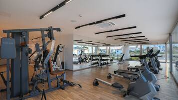 A gym with cardio machines, weightlifting equipment, and a large mirror.