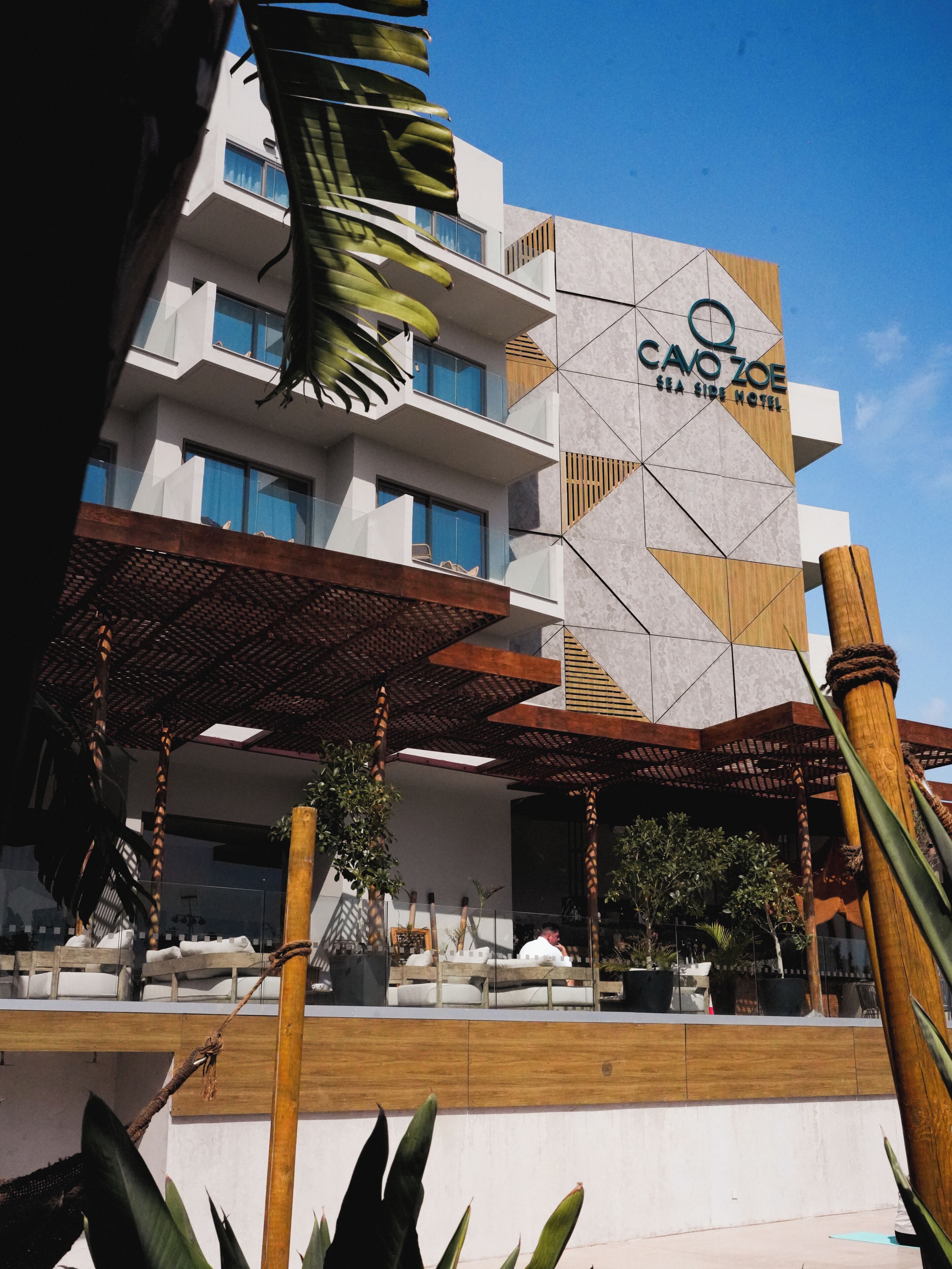 A hotel with a modern design, featuring a geometric facade and a covered outdoor area with seating.