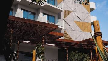 A hotel with a modern design, featuring a geometric facade and a covered outdoor area with seating.