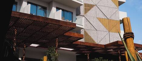 A hotel with a modern design, featuring a geometric facade and a covered outdoor area with seating.