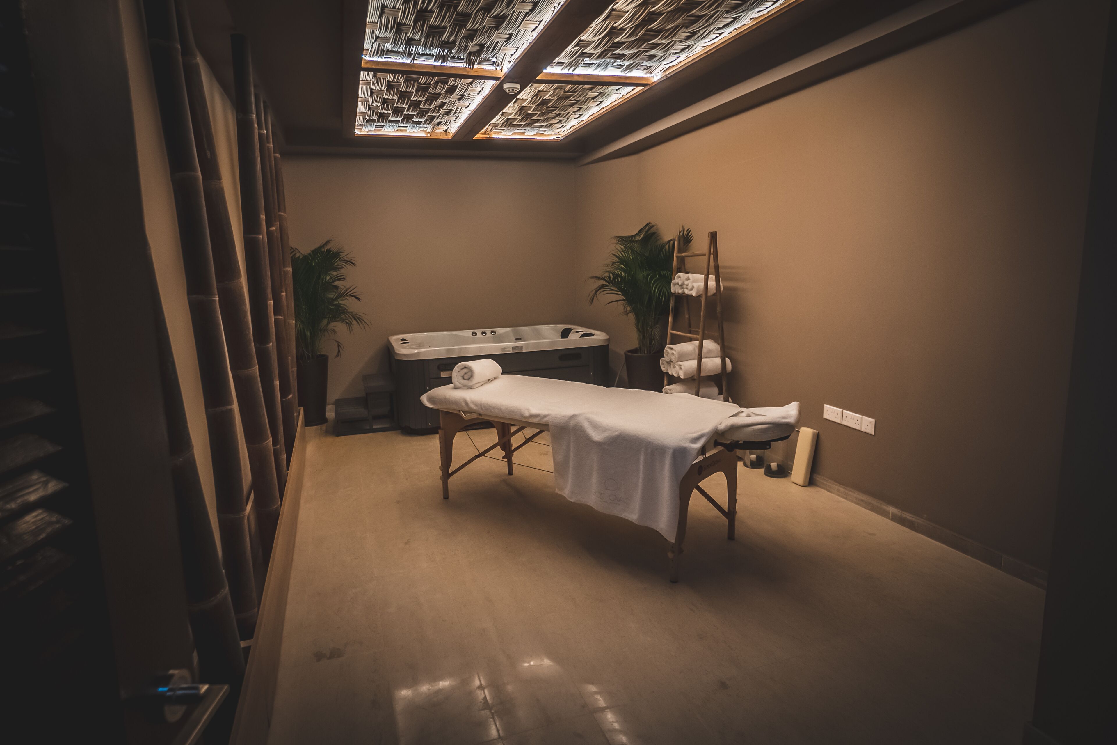 A spa room with a massage table, a hot tub, and a ceiling skylight.