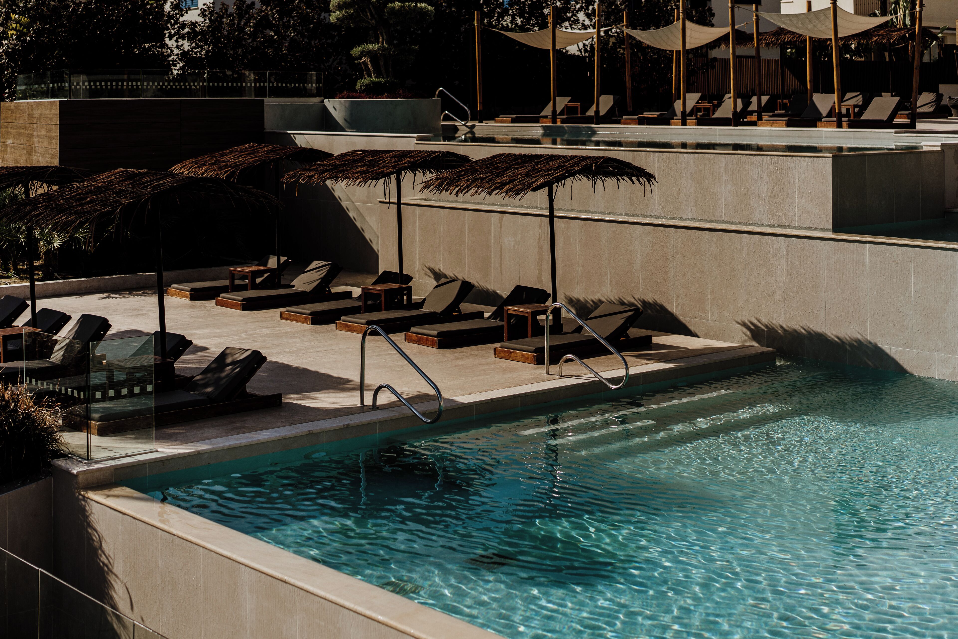 A pool area with lounge chairs and umbrellas.