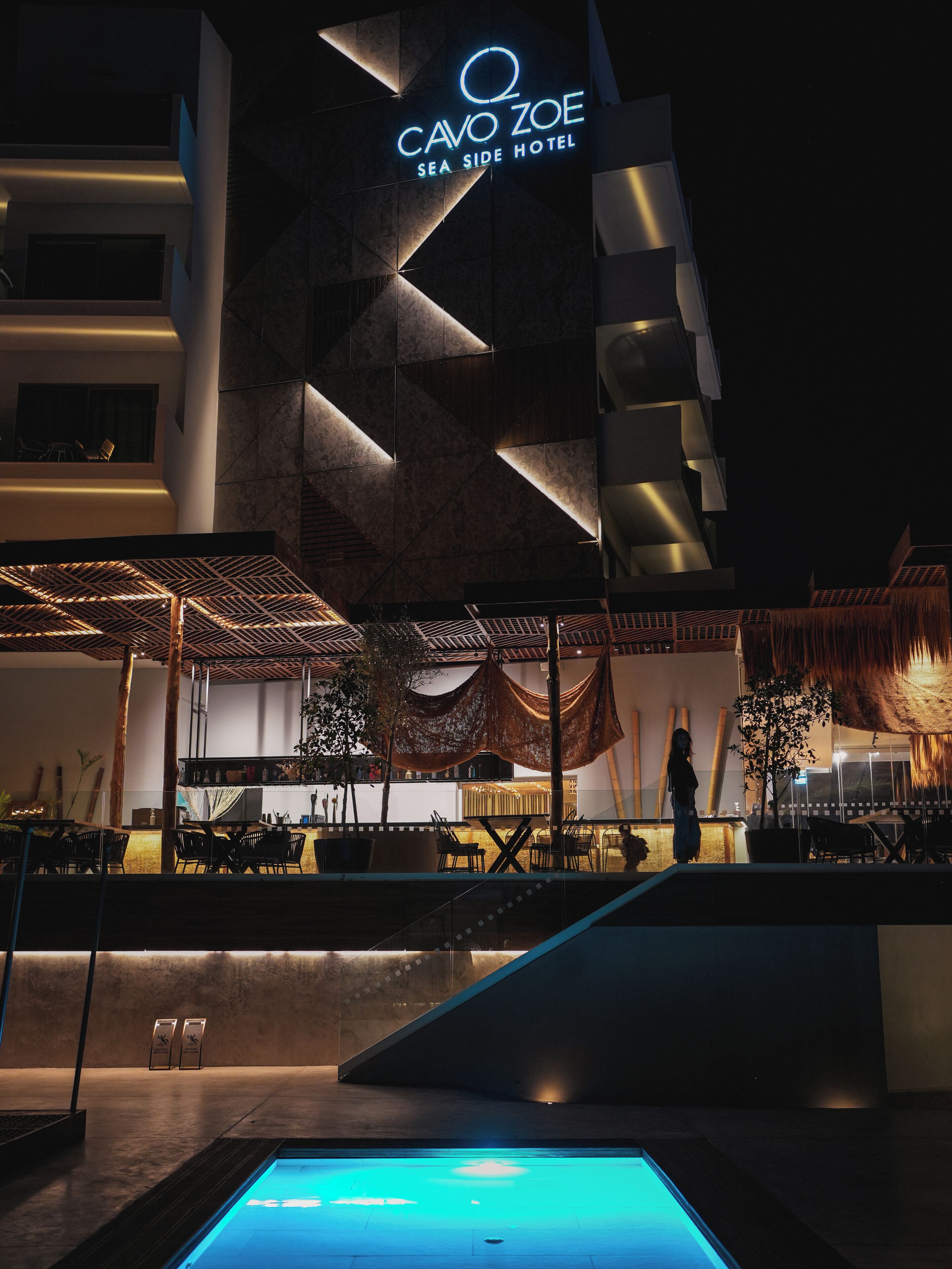 A hotel exterior with a pool, outdoor seating, and a modern architectural design.