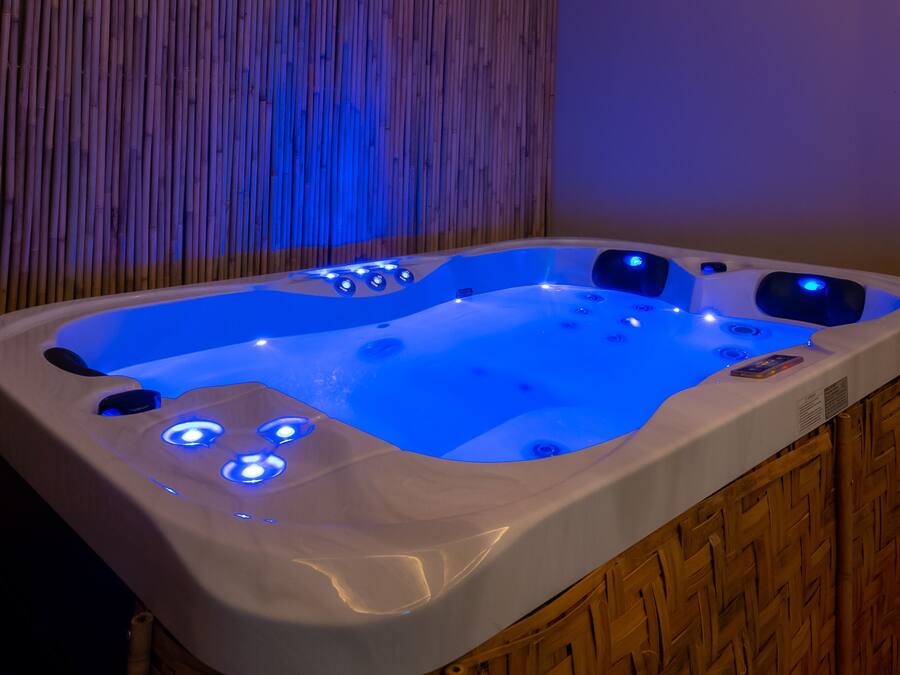 A hot tub with blue LED lights, set against a bamboo backdrop.