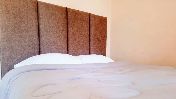 A bed with a headboard and white pillows. - WestPoint Quays (Harare)
