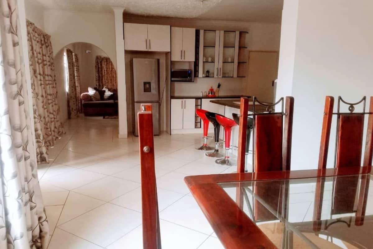 A modern kitchen with white cabinets, a microwave, and a dining area with red bar stools.
