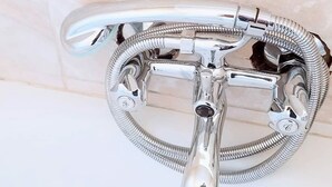 A chrome-finished wall-mounted shower with a flexible hose and a single lever handle. - WestPoint Quays (Harare)