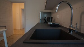 Una cocina moderna con un lavamanos negro, grifo de acero inoxidable y una cafetera sobre la encimera.