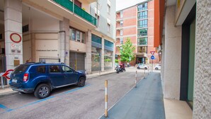 Un coche azul estacionado en una calle urbana estrecha, flanqueada por edificios.