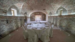 A round table set for a meal in a stone-walled room with arched ceilings and a rustic ambiance. - Tenuta Armonia (Clavesana)