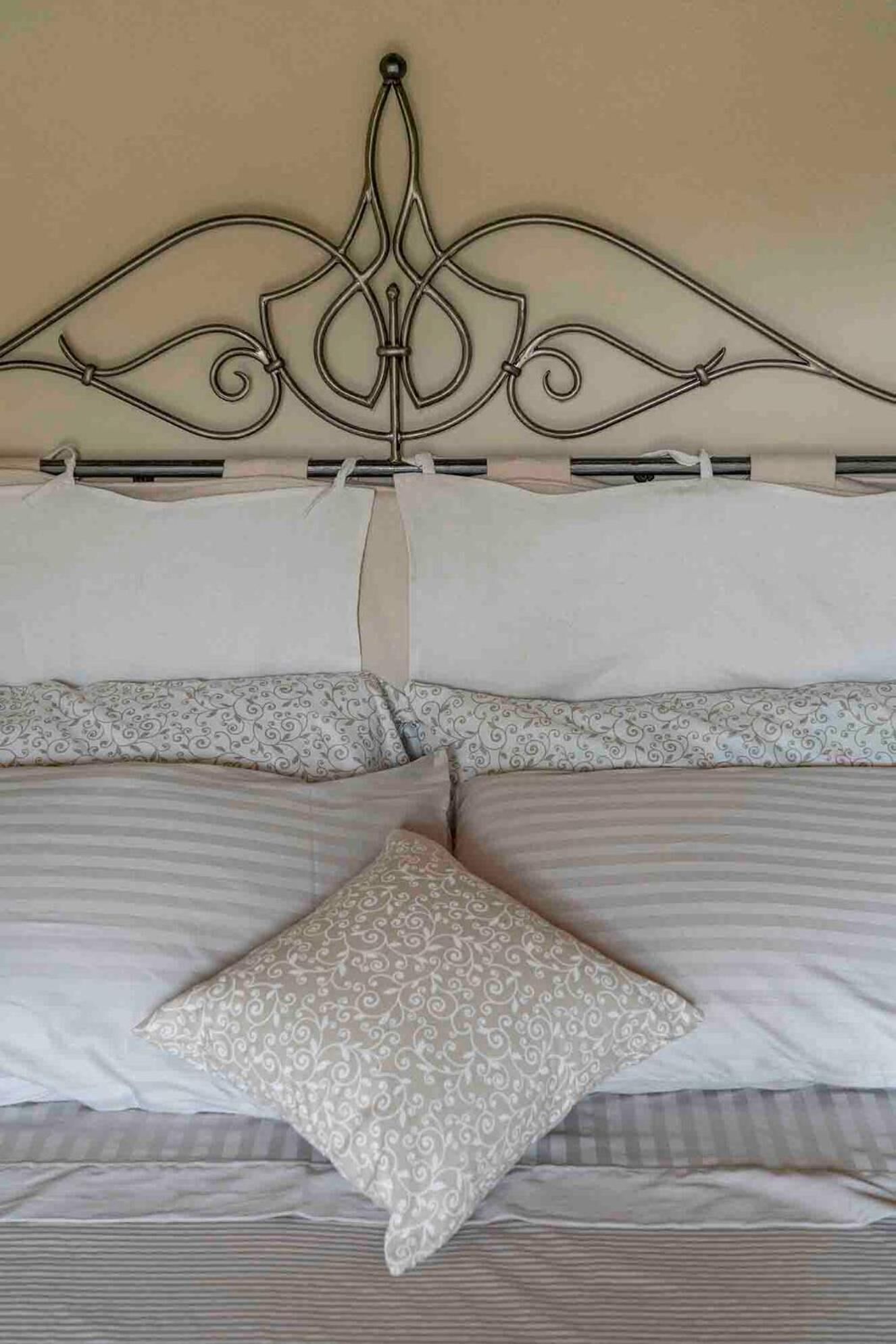 A bed with a decorative metal headboard, two pillows, and a striped bedspread.