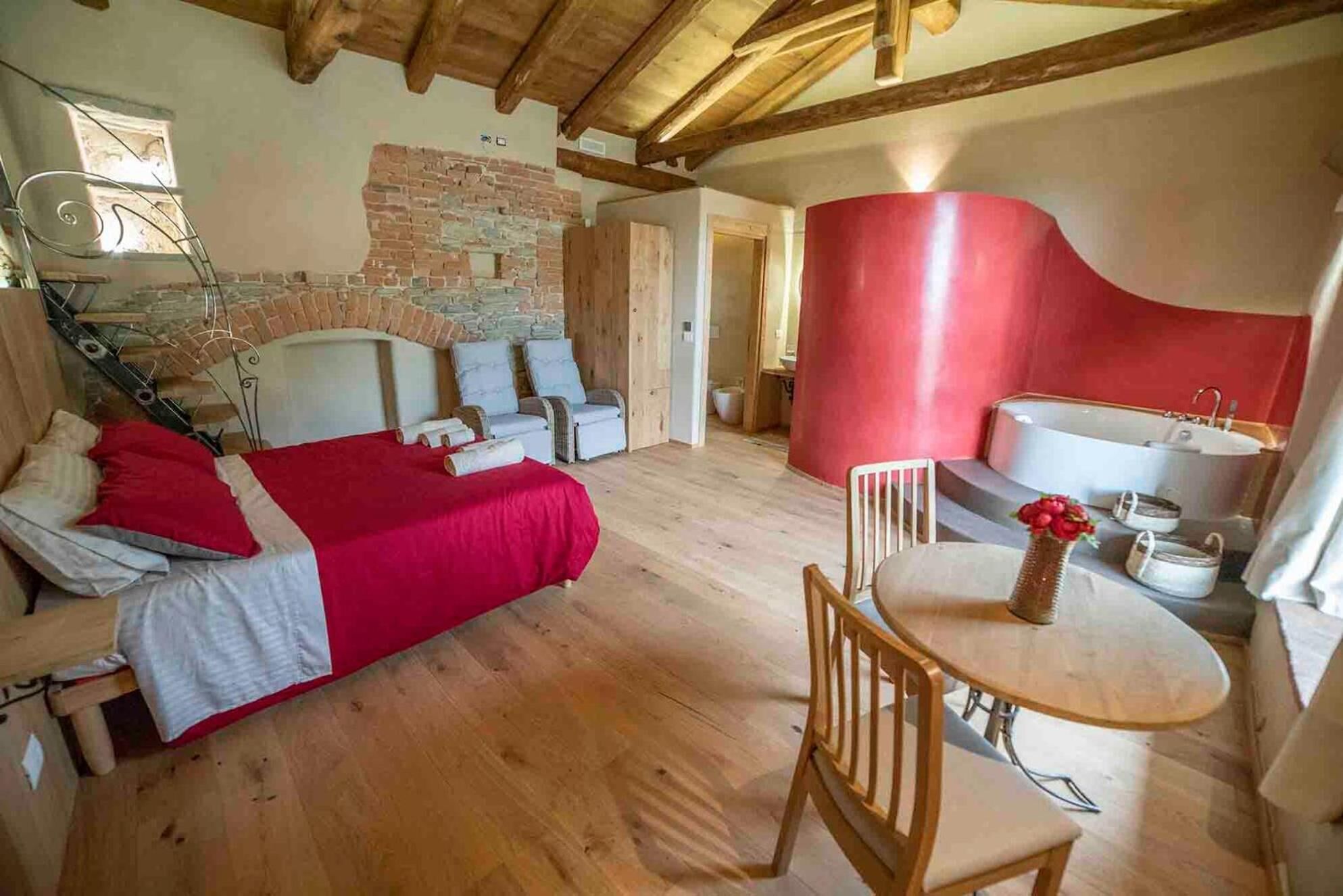 A cozy room with a bed, a seating area with a table, and a red accent wall.