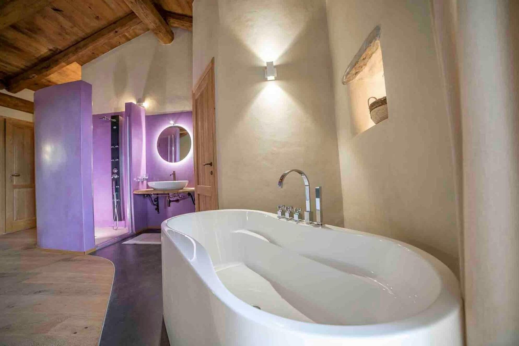 A bathroom with a freestanding bathtub, a round mirror, and a wooden ceiling.