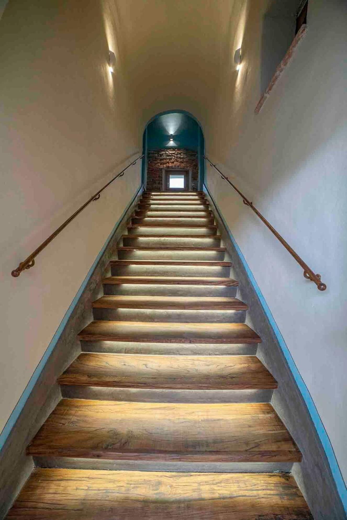 Una escalera de madera con un muro de piedra en la parte superior, que lleva a una puerta.