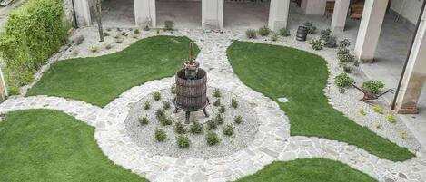 A courtyard with a central fountain, surrounded by stone pathways and green lawns.
