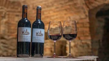 Two bottles of Tenuta Armone wine and two wine glasses on a stone surface with a brick wall in the background.