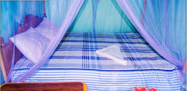 A bed with a blue and white striped bedspread, a white pillow, and a white towel.
