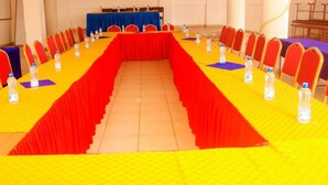 Un salón de conferencias con una larga mesa, sillas y botellas de agua.