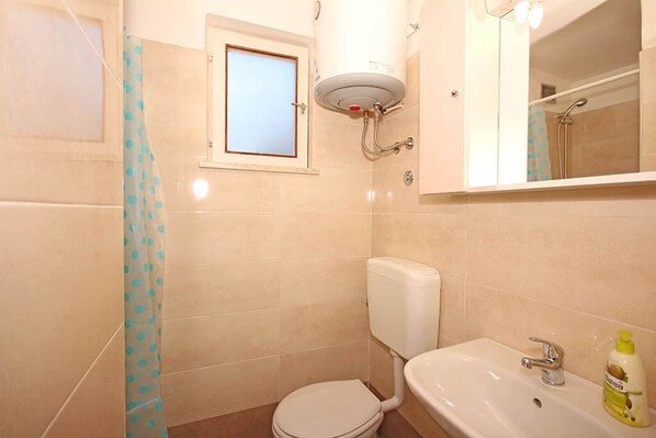 A bathroom with a toilet, sink, and a shower area.