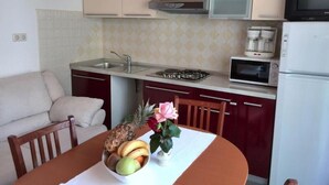 A compact kitchen with a dining area, a microwave, a coffee maker, and a refrigerator.