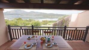 A wooden table set for breakfast with a view of a lake and mountains. - Italianflat - Villa Ca Rosa (Olbia)