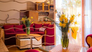 Ein Wohnzimmer mit einem roten Sofa, einem Korbtisch und einer Glasvase mit Blumen.
