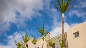 A building with a clear blue sky and palm trees in front. - Villa Familia Chania (Chania)