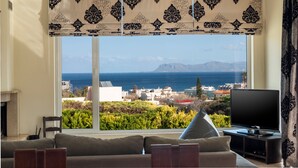 A living room with a large window, a sofa, a television, and a fireplace. - Villa Familia Chania (Chania)