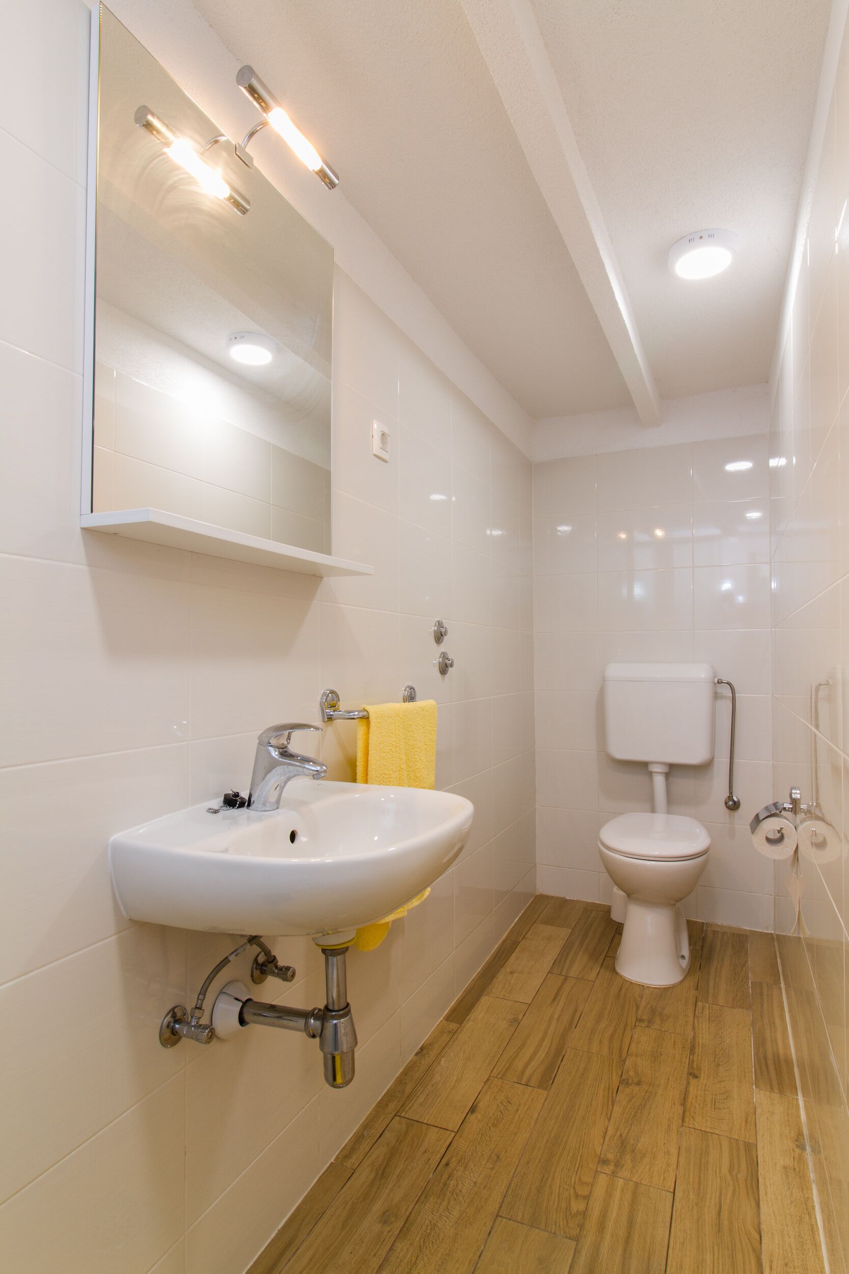 A bathroom with a white sink, mirror, and toilet.