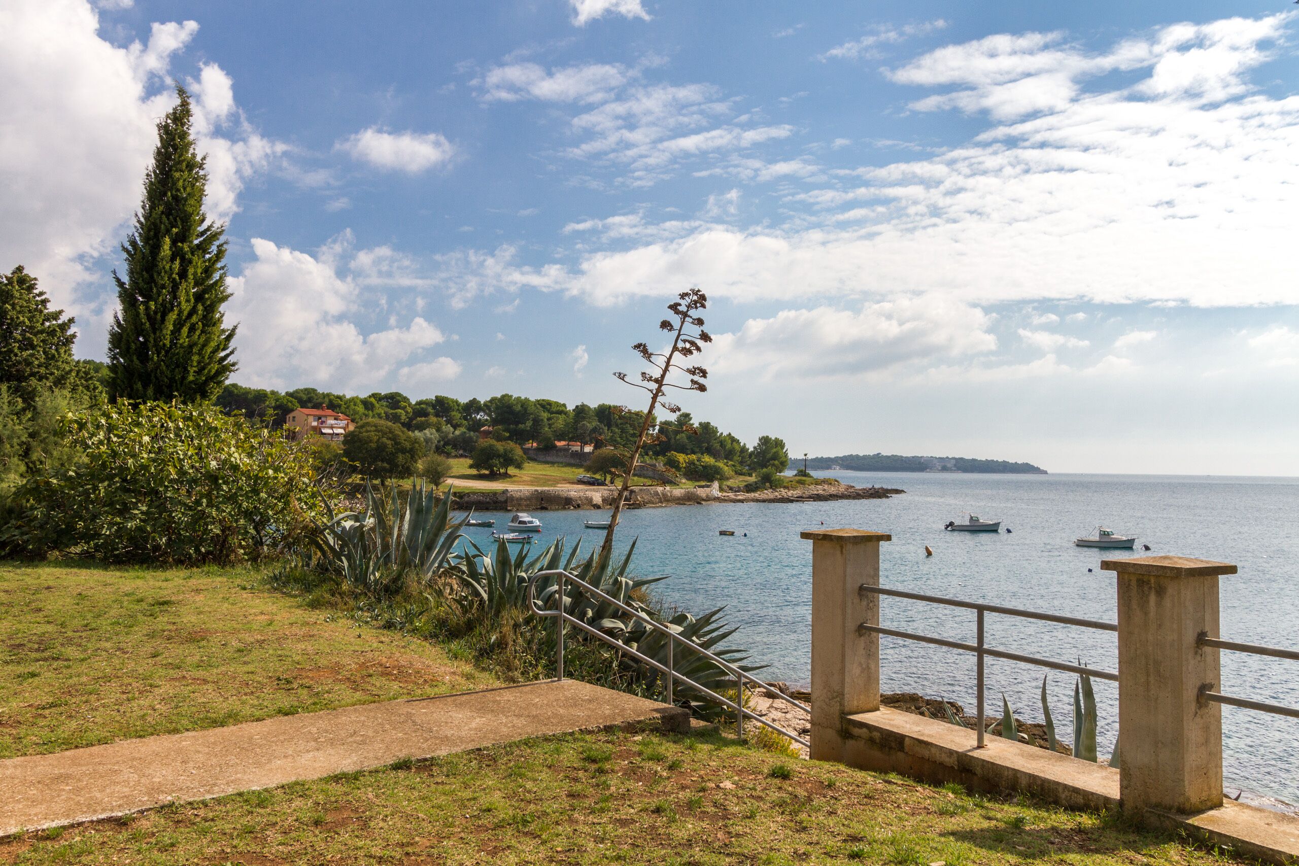 A coastal landscape with a pathway leading to a viewing platform overlooking the sea.