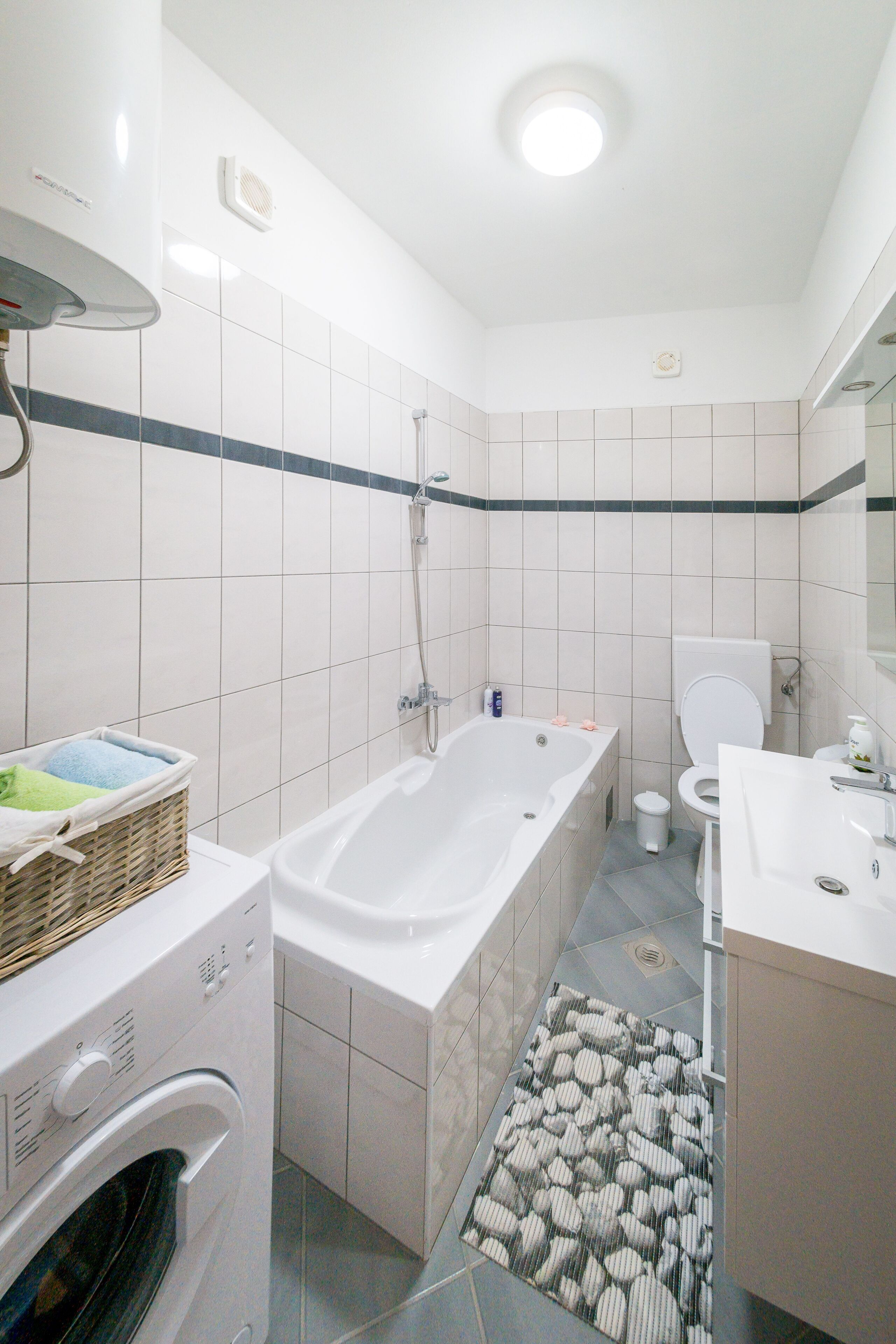A modern bathroom with a bathtub, toilet, and washing machine.