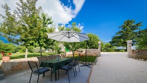 An outdoor patio with a table and chairs, surrounded by stone walls and greenery. - Stone house Furlani with a lovely garden (Svetvincenat)