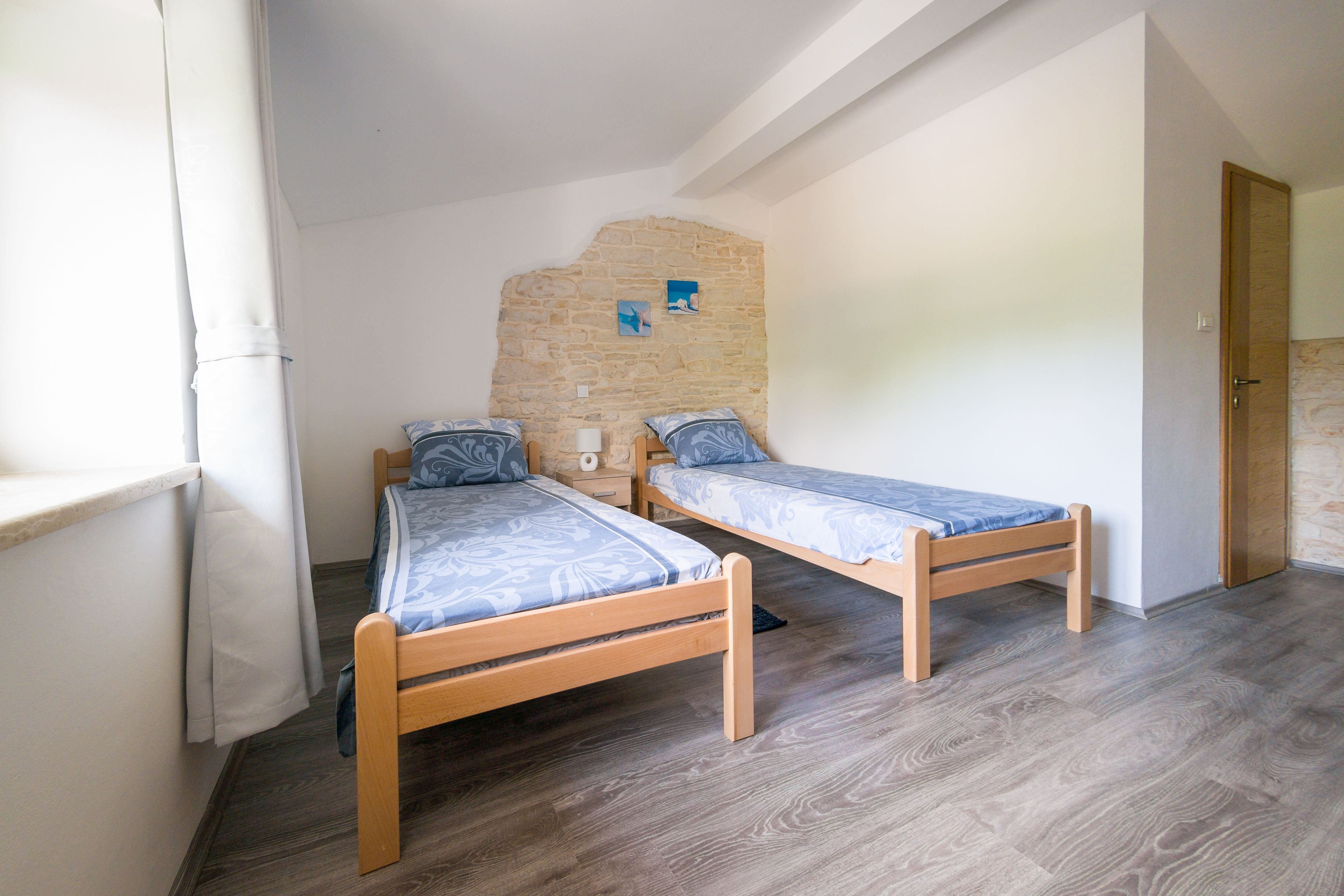 Una habitación con dos camas de madera, una pared de piedra y una puerta.