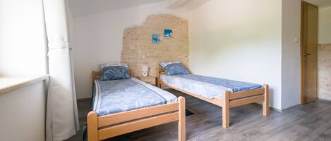 Una habitación con dos camas de madera, una pared de piedra y una puerta.