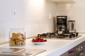 A kitchen with a white countertop, a glass jar of cookies, and a bowl of strawberries. - Charming and sweet apartment Vito (Pula)