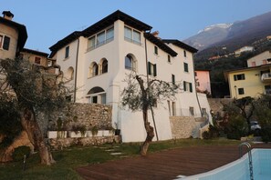 A two-story building with a stone facade, arched windows, and a wooden deck in front.