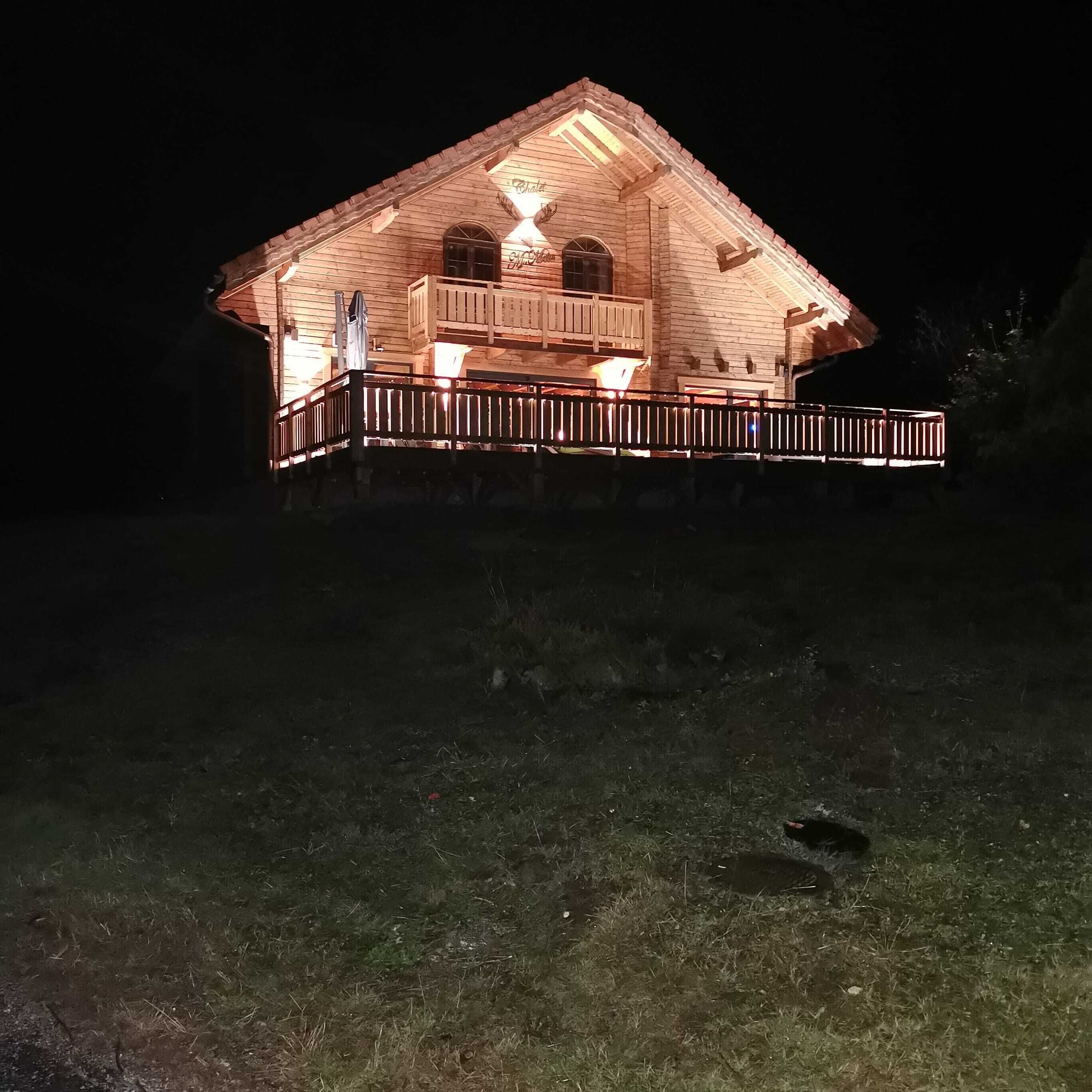 Ein hölzernes Gebäude mit einem Balkon, beleuchtet bei Nacht.