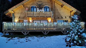 Une cabane en rondins dotée d’un balcon, entourée de neige.