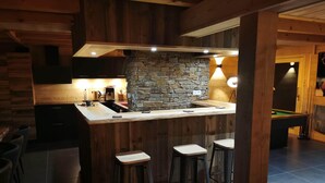 Une cuisine moderne avec un mur recouvert de pierres, des éléments décoratifs en bois et des tabourets de bar.