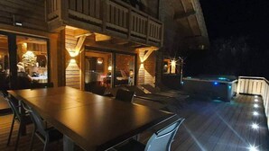 Une terrasse extérieure avec une table et des chaises pour les repas, un barbecue et un espace salon couvert avec balcon.