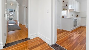 A spacious kitchen with white cabinetry and a wooden floor.