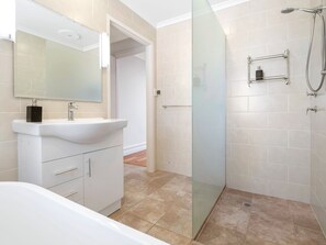 Een moderne badkamer met een wit wastafelmeubel, een douchecabine met glazen wanden en een grote spiegel.
