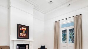 A bedroom with a large bed, a fireplace, a chair, and a window with curtains.