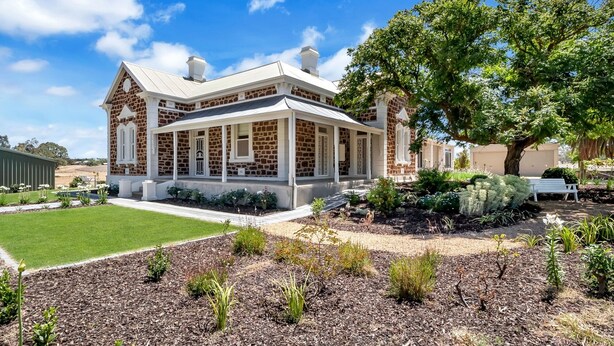 A stone building with a covered porch and a landscaped garden.