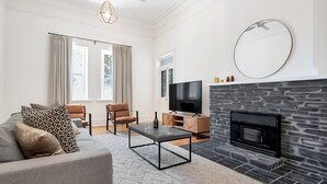 A living room with a stone fireplace, a flat-screen TV, a sofa, and a coffee table.