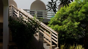 A staircase with wooden railings leading to a building with a white facade and arched windows. - Opera Hotel (Nungwi)