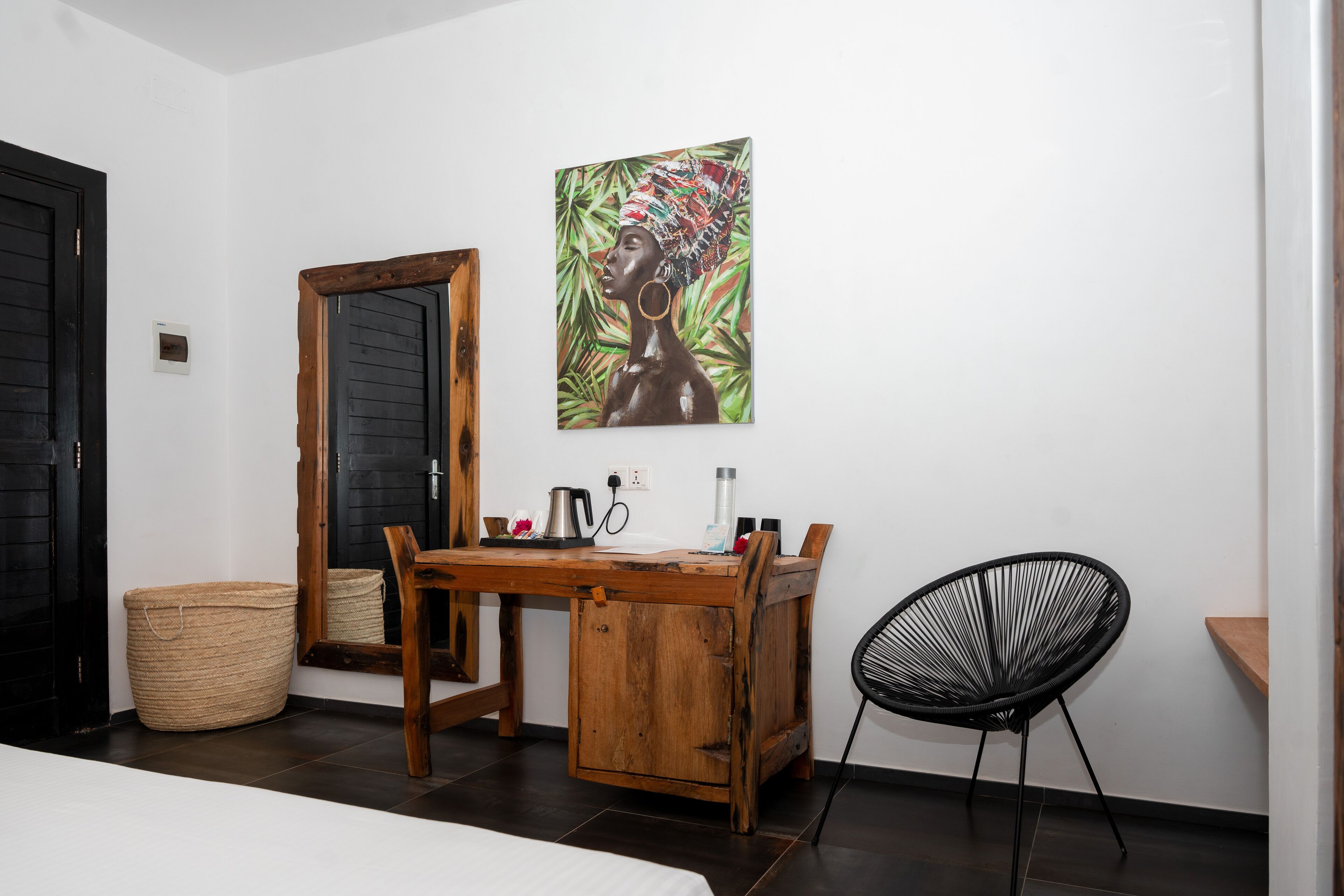 Une pièce avec un bureau en bois, une chaise noire, un grand miroir et un tableau accroché au mur.