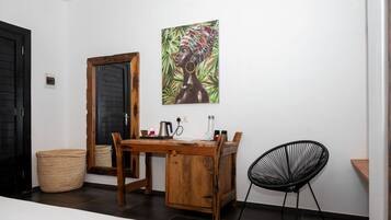Une pièce avec un bureau en bois, une chaise noire, un grand miroir et un tableau accroché au mur.
