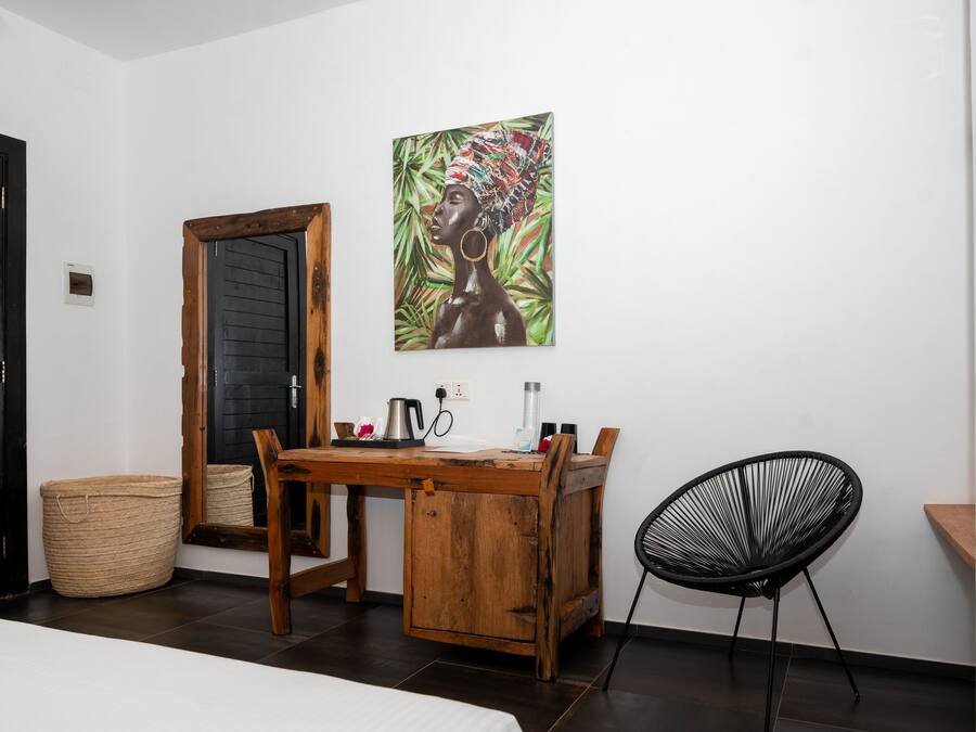 Une pièce avec un bureau en bois, une chaise noire, un grand miroir et un tableau accroché au mur.